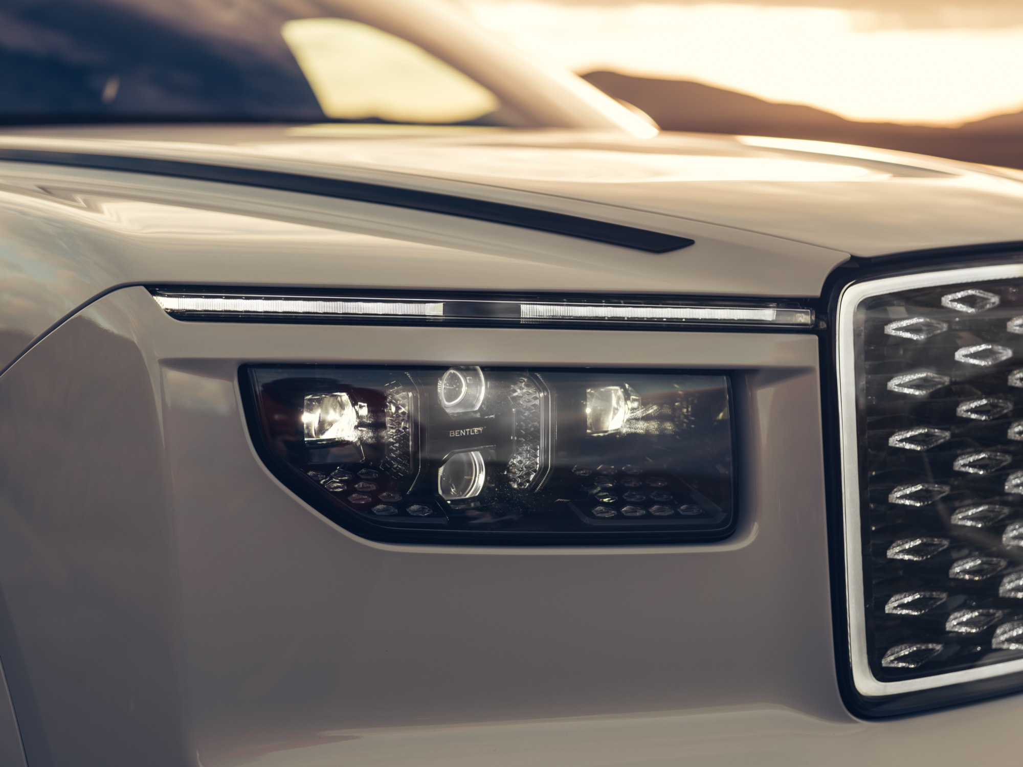 A headlamp beside the diamond grille